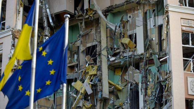 Флаги ЕС и Украины в Киеве рядом с разрушенным зданием