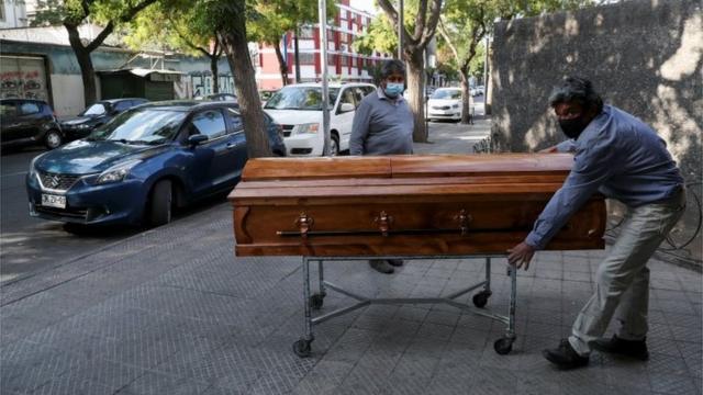 Работники похоронного бюро у морга при одной из больниц в Сантьяго 8 апреля