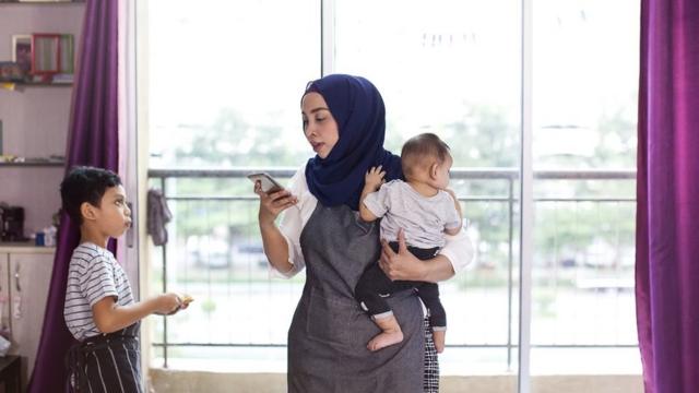 Multi-tasking mother with smart phone and kids