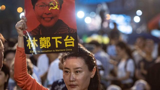 Женщина держит в руках портрет главы администрации Гонконга Кэрри Лам