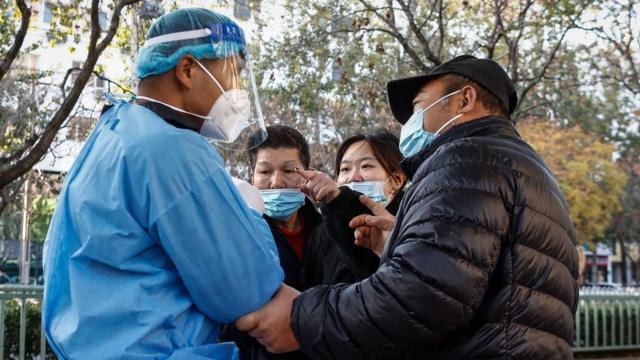 A woman (2-R) argues with a volunteer health worker (L) at a COVID-19 test site in Beijing, China, 21 November 2022