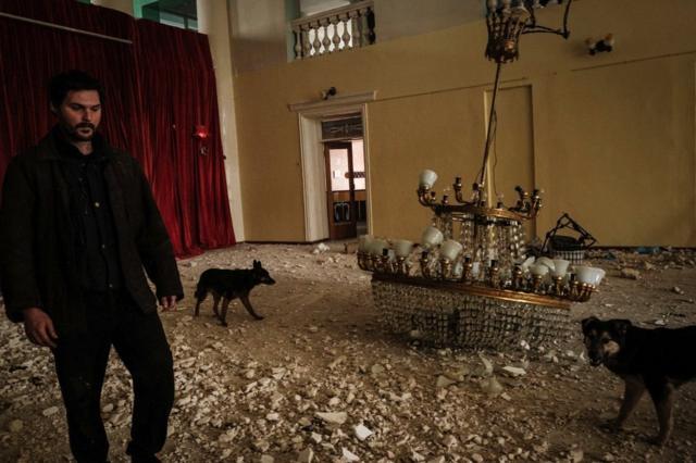 An internally displaced man walks with dogs in the destroyed building of the Palace of culture by shelling in Rubizhne, eastern Ukraine, on April 23, 2022 amid the Russian invasion of Ukraine.