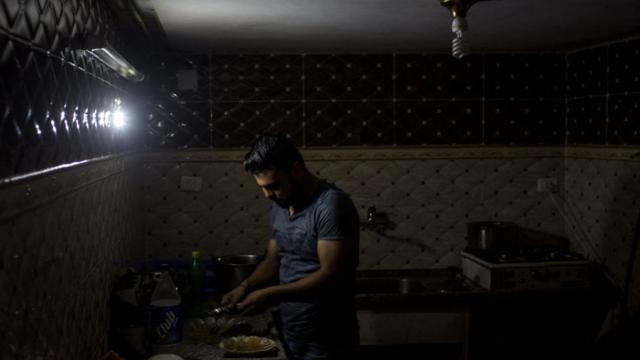 Палестинец в Газе готовит еду практически в темноте