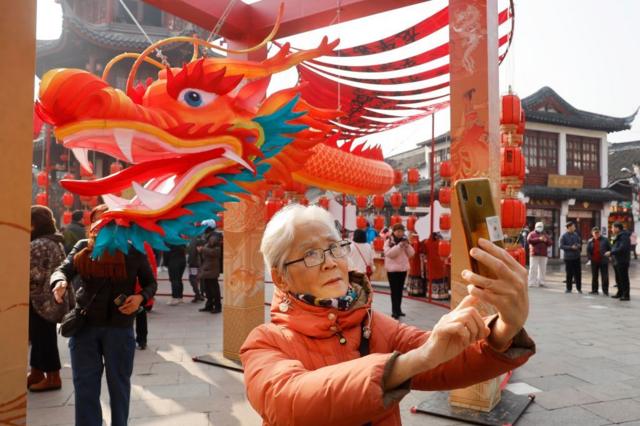 Жительница Шанхая делает селфи на фоне фигуры Дракона