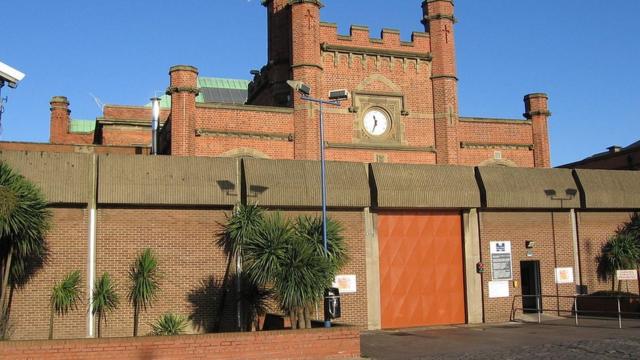 Вход в тюрьму, краснокирпичное здание с часами и закрытыми воротами