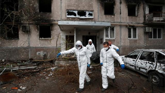 Сотрудники МЧС Украины выносят тело из дома