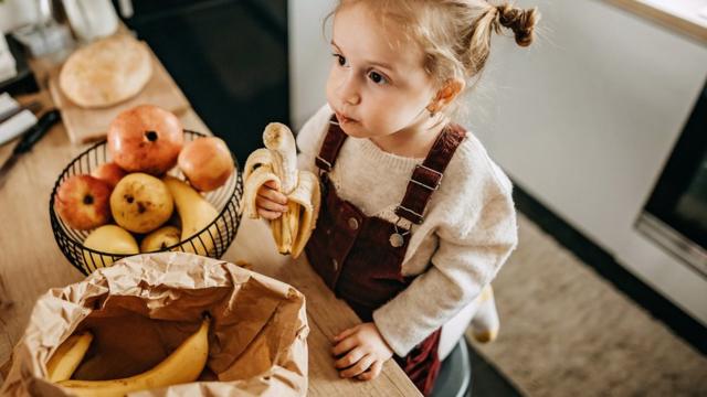 Niña comiendo un plátano