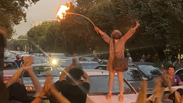 Женщина сжигает свой головной платок во время акции протеста в Тегеране в понедельник