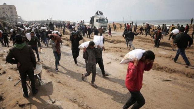 Des Palestiniens transportent des sacs de farine depuis un camion d'aide dans la ville de Gaza.