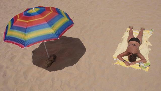 Женщина на пляже и тень от зонтика