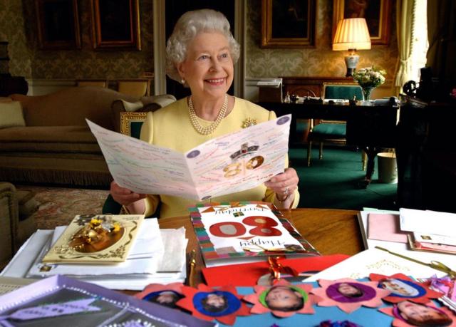 Queen Elizabeth II sits in the Regency Room at Buckingham Palace in London as she looks at some of the cards which have been sent to her for her 80th birthday