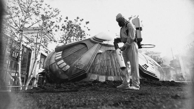 Черно-белый кадр из фильма, человек рядом с летающей тарелкой
