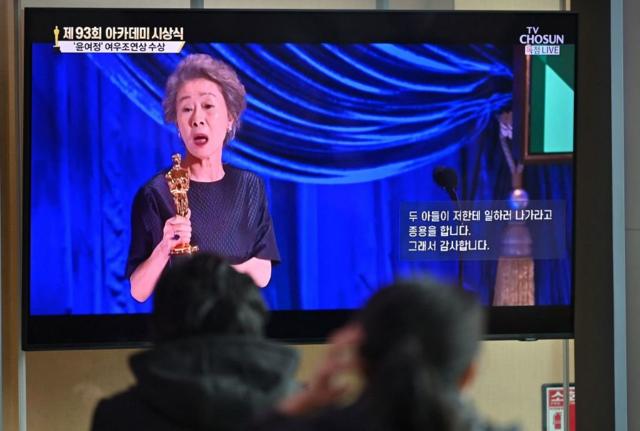 В здании главного вокзала в Сеуле люди с восторгом наблюдают за тем, как корейская актриса Юн Ёджон получает "Оскара" на церемонии в Лос-Анджелесе