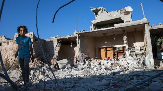 Девочка у руин своего дома в Идлибе. Конфликт в Сирии, начавшийся с антиправительственных выступлений, перерос в гражданскую войну, а затем и в международный конфликт с участием нескольких игроков.