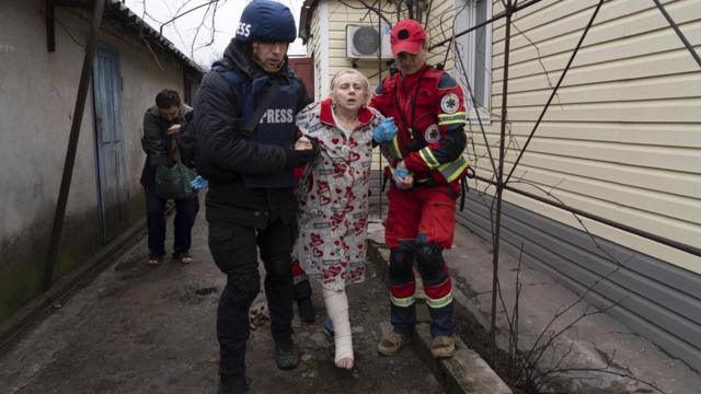Євген Малолєтка допомагає парамедику транспортувати жінку, яка постраждала під час обстрілу в Маріуполі, 2 березня 2022 року (фотографія Мстислава Чернова)