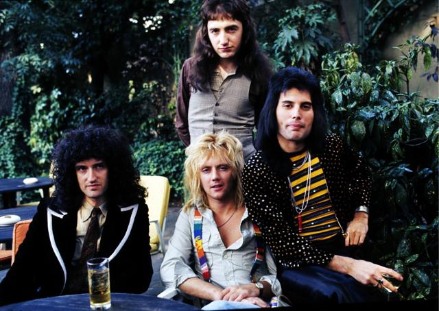 Brian May, John Deacon (standing), Roger Taylor and Freddie Mercury of British rock group Queen at Les Ambassadeurs where they were presented with silver, gold and platinum discs for sales in excess of one million of their hit single 'Bohemian Rhapsody', which was No 1 for 9 weeks on September 8, 1976 in London, England