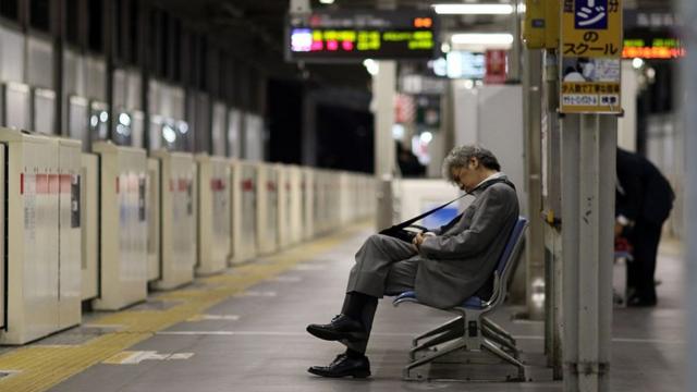 Офисный сотрудник спит на скамейке на вокзале в Токио