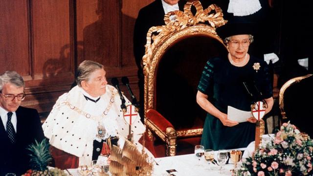 Королева выступает с речью за столом, рядом с нею сидят Лорд-Мэр Сити и премьер Джон Мейджор