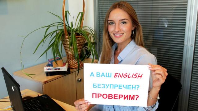Девушка с табличкой "А ваш English безупречен? Проверим?" / Уроки английского языка, аудио, видео и тесты: как учить и проверять английский с Би-би-си