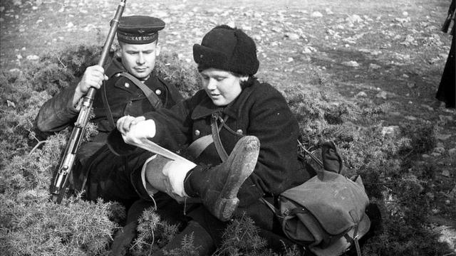 Медсестра оказывает помощь раненому краснофлотцу, на ногах которого ботинки, присланные по ленд-лизу, 1942 г.