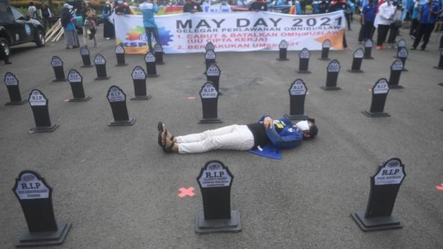 Участник демонстрации в Джакарте, лежащий на асфальте