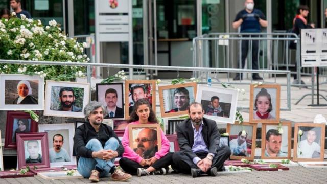 Участники пикета около суда демонстрируют фотографии жертв преступлений, совершенных в Сирии, лето 2020 года