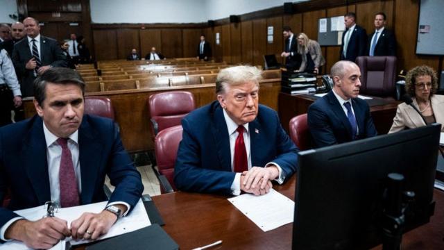 Donald Trump duduk di meja terdakwa dengan tim hukumnya dalam persidangan.
