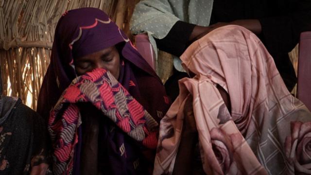 Des femmes s'essuient les yeux avec leur hijab lors d'une réunion dans un camp de réfugiés.