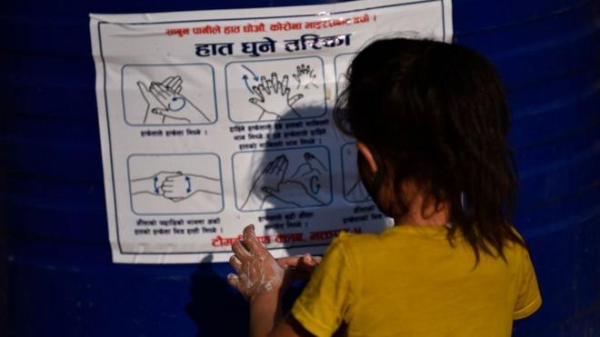 Непальская девочка перед плакатом о правильном мытье рук
