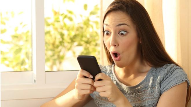 Woman looking surprised at smartphone
