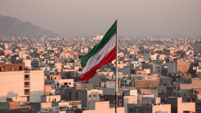 Iranian flag waving with cityscape on background in Tehran, Iran