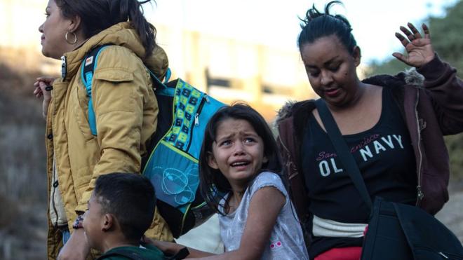 Група мігрантів з Центральної Америки здалася американським прикордонникам після того, як вони перестрибнули через металевий бар'єр, що відокремлює Плайса де Тіхуана в Мексиці від США, 2 грудня 2018 р.