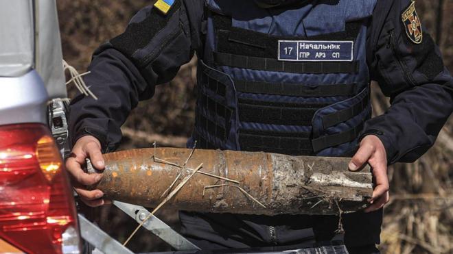 Украинский военный несет неразорвавшийся снаряд в Бородянке