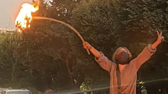 Женщина сжигает свой головной платок во время акции протеста в Тегеране в понедельник