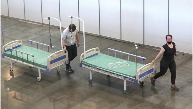 Сотрудники везут кровати во временном госпитале для больных с коронавирусом в выставочном павильоне "Крокус Экспо"