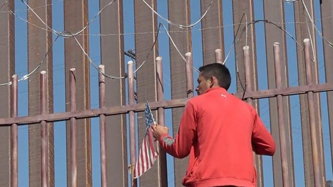 Мигрант лезет на забор на границе США и Мексики