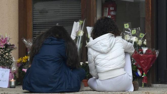 Youngsters look at floral tributes laid at the school in Conflans Saint-Honorine where the murdered teacher was from, on 17 October 2020