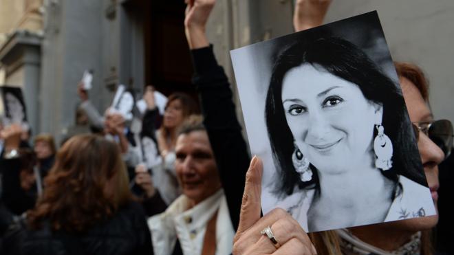 Campaigners holding up photos of Daphne Caruana Galizia