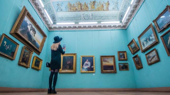 Відвідувачка фотографує картини в Одеському художньому музеї