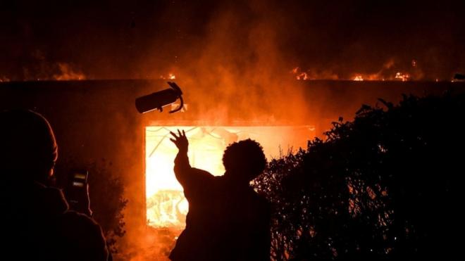 A protester throws a fire extinguisher into a burning building overnight in Minneapolis