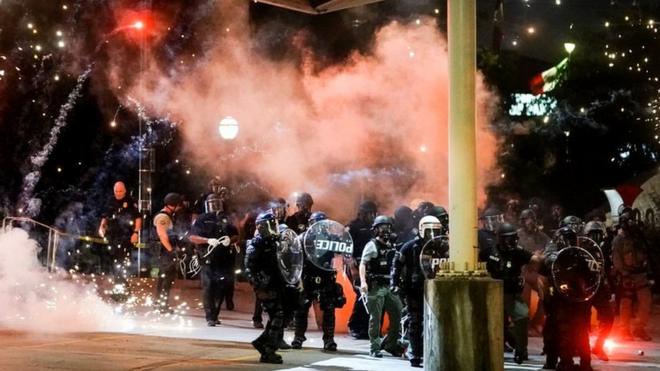 A firework explodes near a police line during a protest in Atlanta, Georgia, in response to the police killing of George Floyd, 30 May 2020