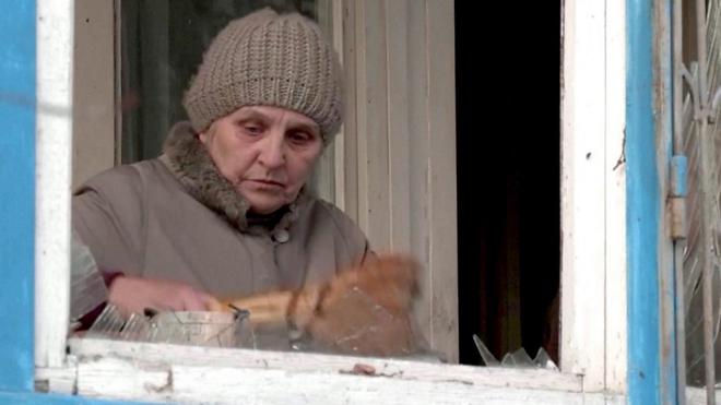 пожилая женщина у разбитого окна