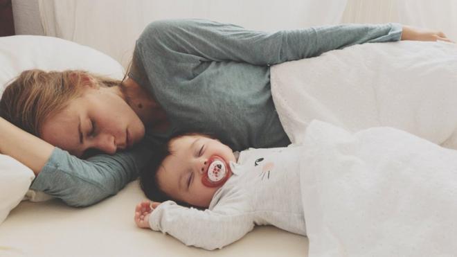 Mother And Son Sleeping On Bed At Home