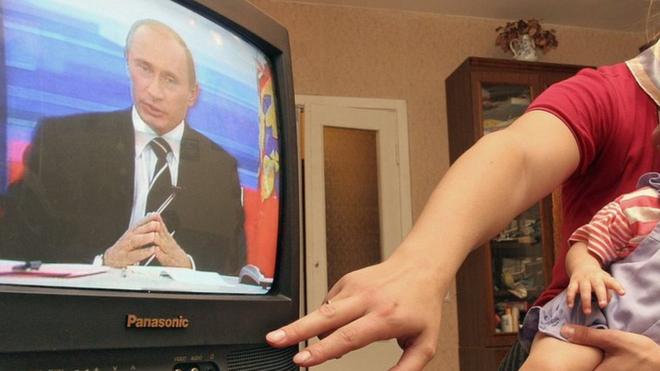 Woman and child watching Putin on TV