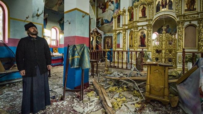 The priest of Yasnohorodka, stands inside his church destroyed because the combats between the Russian and Ukrainian armies