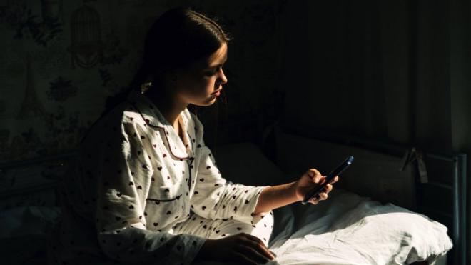 young woman on her phone in bed
