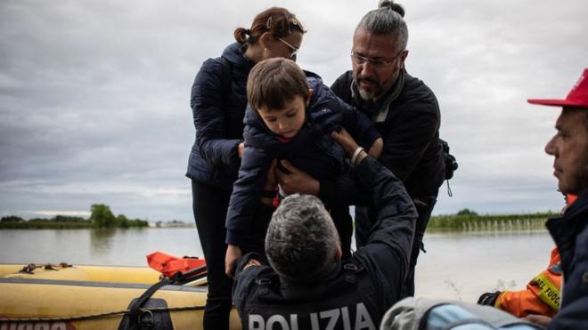 A policeman holds a boy during rescuing operations on May 17, 2023 in Massa Lombarda, a small village about 10 kilometers from Imola,