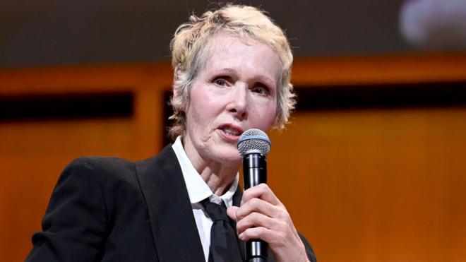 E Jean Carroll speaking into a microphone at a 2019 panel in New York City
