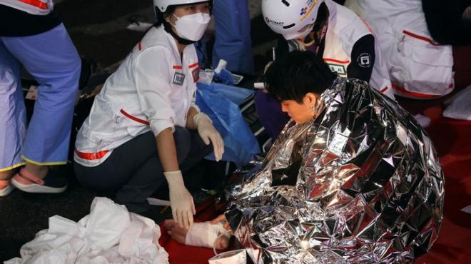 A man receives medical help from rescue team members at the scene where dozens of people were injured in a stampede during a Halloween festival in Seoul, South Korea, October 29, 2022