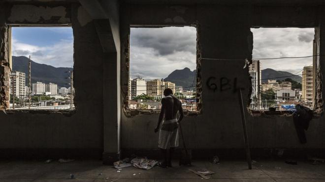 A man stands at the windows of the abandoned Ministry of Finance building (now an occupied building/squat) in the 'Favela' Mangueira community, North Zone, Rio de Janeiro, Brazil